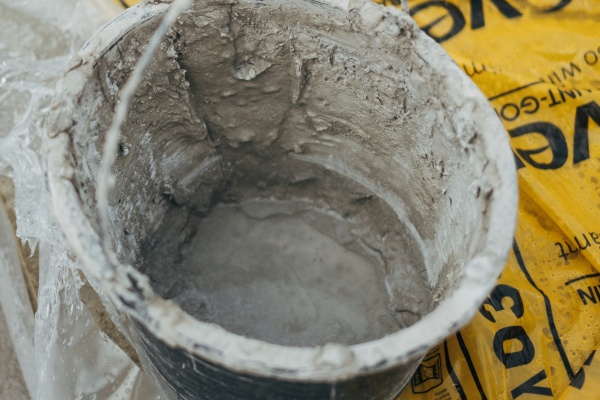 Aangemaakte gietmortel in een emmer op bouwfolie tijdens betonreparatie